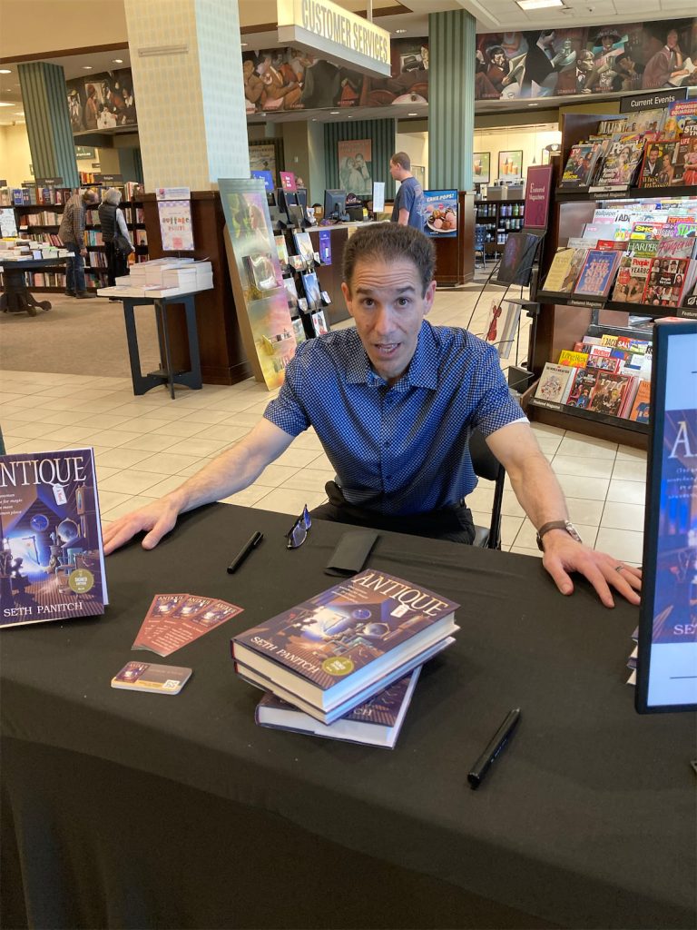 Seth Panitch Sitting at table with his book Antique.
